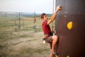 Sporty man practicing rock climbing in gym on artificial rock training wall outdoors. Young talanted climber guy on Royalty Free Stock Photo
