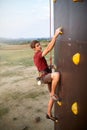 Sporty man practicing rock climbing in gym on artificial rock training wall outdoors. Young talanted climber guy on Royalty Free Stock Photo