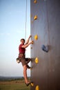 Sporty man practicing rock climbing in gym on artificial rock training wall outdoors. Young talanted climber guy on Royalty Free Stock Photo