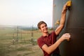 Sporty man practicing rock climbing in gym on artificial rock training wall outdoors. Young talanted smiling climber guy Royalty Free Stock Photo