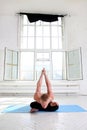 Sporty man practicing yoga in white room with big window