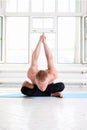 Sporty man practicing yoga in white room with big window
