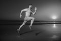 Sporty man runner running in summer sea beach. Attractive fit man run on sunset light, workout outdoors, jogging with Royalty Free Stock Photo