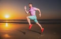 Sporty man runner running in summer sea beach. Attractive fit man run on sunset light, workout outdoors, jogging with Royalty Free Stock Photo