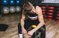 Sporty man sitting on sandbag relaxing after exercises in the gym. Attractive athletic male rest after hard workout with weight