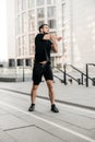 Sporty man stretching arms before jogging. Runner in black sportswear excercising at morning. Healthy lifestyle concept Royalty Free Stock Photo