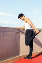 Sporty man stretching leg muscles on concrete wall