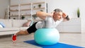 Sporty mature man doing exercises with fitness ball at home, working out his back muscles, panorama, copy space Royalty Free Stock Photo
