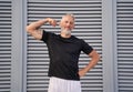 Sporty mature man looking at camera, showing his muscular arm and bicep while standing outdoors over gray background Royalty Free Stock Photo