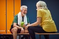 Sporty mature man and woman in gym locker room sitting facing each other and having a joyful conversation Royalty Free Stock Photo