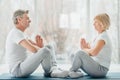 Sporty middle aged couple sitting on the mat in the white fitness gym and doing stretching while looking each other.Sports and Royalty Free Stock Photo