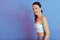 Sporty model with perfect body posing isolated over blue background, female wearing white bra and gray leggins, lady with ponytail Royalty Free Stock Photo