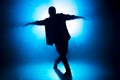 Sporty modern style hip-hop dancer shows his dance on blue studio background.