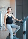 Sporty pregnant woman exercising in fitness room with smiling and looking at camera