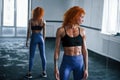 Sporty redhead girl have fitness day in gym at daytime. Muscular body type Royalty Free Stock Photo