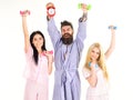 Sporty regime concept. Man in robe, trainer holds clock, attractive young women in pajamas doing exercises with