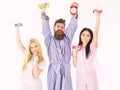 Sporty regime concept. Man in robe, trainer holds clock, attractive young women in pajamas doing exercises with