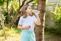 Sporty school age child, girl drinking fresh clear filtered water from a reusable plastic bottle outdoors, copy space, side view Royalty Free Stock Photo