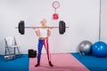 sporty senior lady lifting barbell and looking