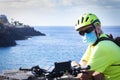 Sporty senior man with bike helmet and medical mask to avoid coronavirus infection. Use an electric bike. Horizon over the water Royalty Free Stock Photo