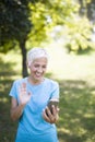 Sporty senior woman using mobile phone in the park