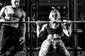 Sporty sexy couple with barbell in gym. Sportive couple in gym. Personal trainer helping woman doing exercise. Royalty Free Stock Photo