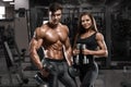 Sporty couple showing muscle and workout in gym. Muscular man and woman