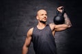 Sporty shaved head tattooed male doing shoulder workout with the Kettlebell.