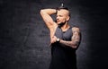 Sporty shaved head tattooed male doing triceps workout with dumbbell.