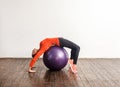 Sporty slim young woman in tight sportswear bending over big fitness rubber ball, stretching and exercising abdomen muscles Royalty Free Stock Photo