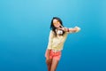 Sporty tanned girl in denim shorts posing on bright blue background with pleasure. Indoor portrait of magnificent