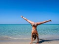 Sporty tanned girl doing a cartwheel on a wonderful beach with turquoise water - gymnastic Royalty Free Stock Photo