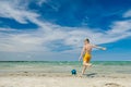 Sporty teen boy playing with ball on beach at summer day with beautiful blue sky during summer holidays Royalty Free Stock Photo