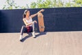 Sporty teen girl with skateboard listening music. Outdoors, urban lifestyle