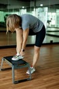 A sporty woman adjusts her shoes or ties her shoelaces on a bench. Photo of an attractive woman in sportswear. Strength