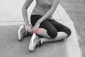 Sporty woman ankle sprain while jogging or running at park - black and white concept.