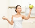 Sporty woman with apple and cake in kitchen Royalty Free Stock Photo