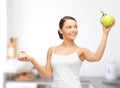 Sporty woman with apple and cake in kitchen Royalty Free Stock Photo