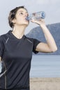 Sporty woman brunette drinking water in a beach. Royalty Free Stock Photo