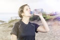 Sporty woman brunette drinking water in a beach. Royalty Free Stock Photo