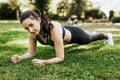 Sporty woman do exercise on green grass look in camera