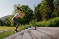 Sporty woman doing jumping squats exercise on stairs in city park. Royalty Free Stock Photo