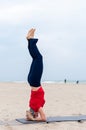 Sporty woman doing Supported Headstand, yoga asana Sirsasana, Shirshasana, Sirshasana, Headstand on sea background Royalty Free Stock Photo
