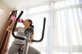 A sporty woman drinking water after cardio workout on a stationary bike to stay hydrated Royalty Free Stock Photo