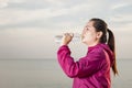 Sporty woman drinking water outdoor on the beach during sunset Royalty Free Stock Photo
