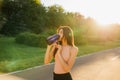 Sporty woman drinking water outdoor at sunset Royalty Free Stock Photo