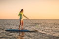 Sporty woman floating at stand up paddle board with colorful sunset colors Royalty Free Stock Photo