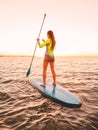 Slim woman floating at stand up paddle board in sea with warm sunset colors Royalty Free Stock Photo