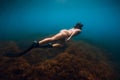 Sporty woman freediver with fins glides underwater in blue sea Royalty Free Stock Photo