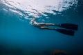 Sporty woman freediver with fins glides underwater in blue sea Royalty Free Stock Photo